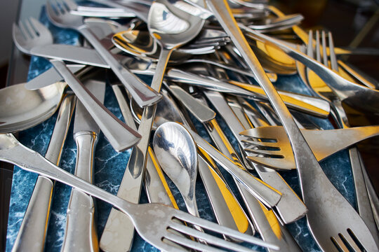 Cutlery. A pile of forks, knives and spoons on a table