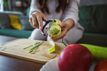 Unknown adult caucasian woman sit on sofa and peel zucchini