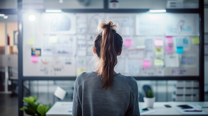 portrait of a female UX designer sketching wireframes on a whiteboard in the IT company office