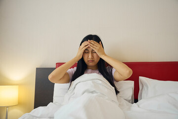 Young female suffering from attack of migraine in bedroom