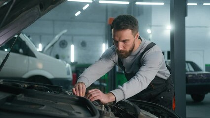 Professional mechanic man Caucasian male guy mechanical engineer specialist in uniform fixing car engine motor repairing electric automobile check auto maintenance in garage service industrial work