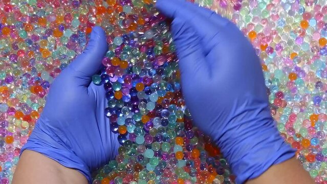 Hands in blue gloves smoothly collect a handful of multicoloredcolorful balls and smoothly scatter multicolored orbis. ASMR part14.14