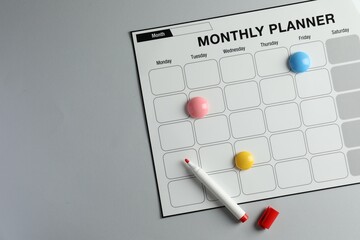 Timetable. Planner with bright magnets and red felt pen on grey table, top view. Space for text