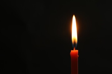 One burning church candle on black background, space for text