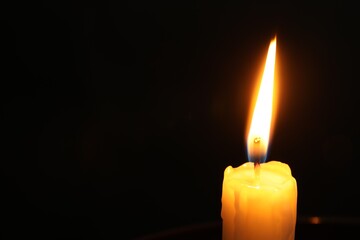 One burning church candle on black background, closeup. Space for text