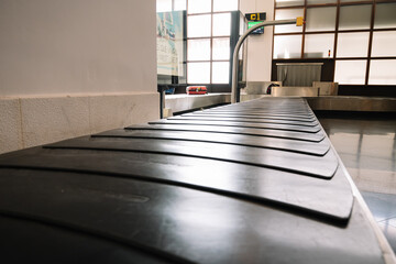 A black conveyor belt with a sign on the wall behind it