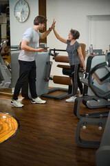 Trainer greets elderly lady in the gym of fitness clinic