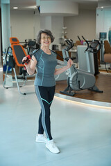 Fototapeta premium Elderly lady stands with a jump rope in a gym