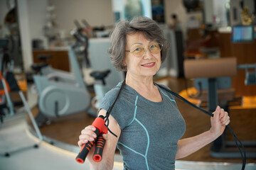 Elderly lady performs special exercises with a skipping rope