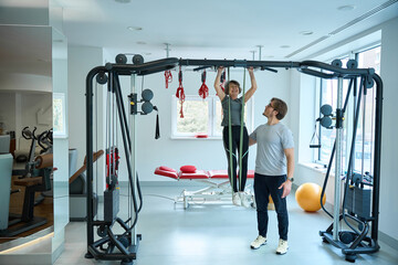 Fototapeta premium Rehabilitologist works with an elderly woman on a suspension system