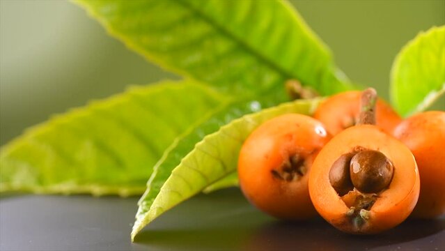 Loquat fruit or Japanese medlars, Nispero, Eriobotrya japonica fresh ripe bio vegetarian food, medlar berries. Close up, slow motion. On black table background 