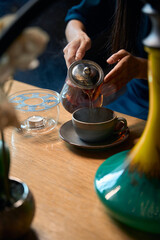 Close-up woman carefully pouring freshly brewed tea into the cup