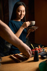 Waiter bringing female order with tasty sushi with ginger and soy sauce