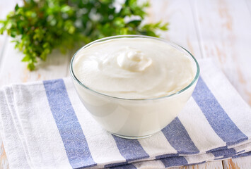 natural organic yogurt in a bowl with spoon on a white table, selective focus.