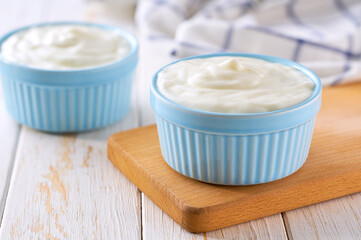 tasty greek yogurt  in a ceramic bowl on a white table, selective focus.