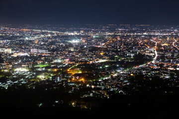 Fototapeta premium Night Chiang Mai view. Illuminated city view at night from the viewpoint on the way to Doi Suthep temple.