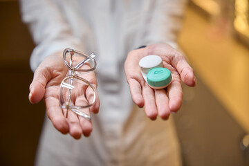 Female consultant holds container with removable lenses and glasses in her hands