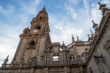 Fototapeta premium A stunning cathedral tower adorned with intricate stonework and spires rises into a blue sky with cirrus clouds, indicative of European Gothic architecture.