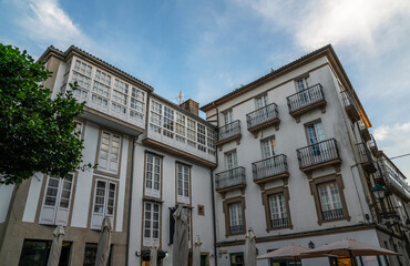 Fototapeta premium Traditional European urban architecture with classic white buildings and glass-enclosed balconies against a blue sky with light clouds.