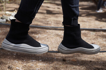 female legs in sneakers walk along a rope low above the ground, close-up