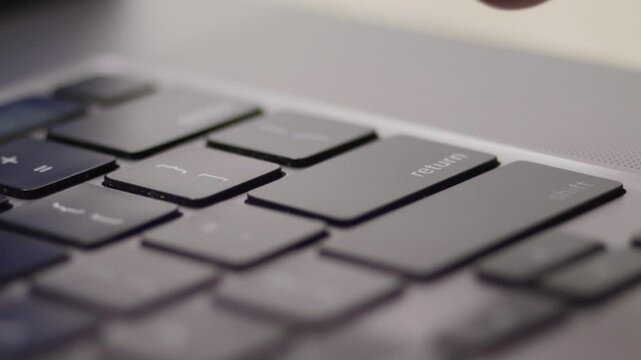 Closeup footage of a finger of an adult hand pressing the return key on the laptop keyboard