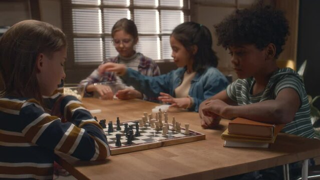 Side shot of young diverse opponents playing chess at board games club. Boy thinking out his next move
