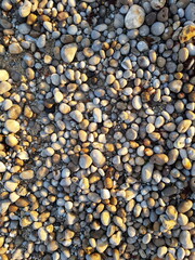 Natural stone pattern background file picture of different sized stones at a beach at golden light of a sunset