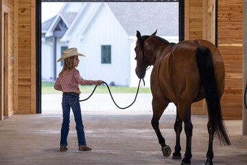 Little girl cowgirl with bay horse