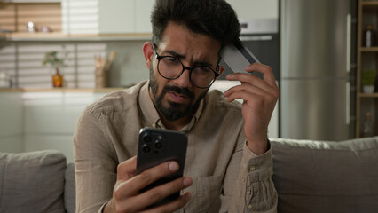 Stressed Arabian Indian man frustrated upset male cardholder pay online service with bank credit...