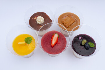 Top view of five  isolated cheescakes in a cup  in black, yellow and red color as a german flag  and brown on light background, fruit dessert to support national sport team