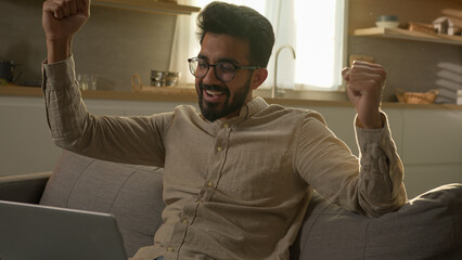 Amazed excited surprised Arabian Indian muslim man home freelancer use laptop computer in domestic...