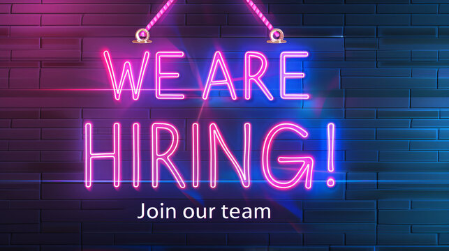 Brick wall at night with neon now hiring sign glowing