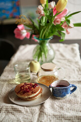 Simple pancake breakfast with jam and apple, tea served on a kitchen table. Simple life concept High quality photo