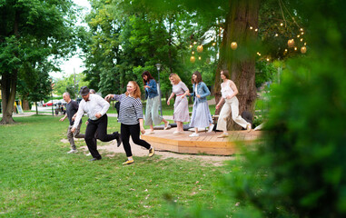 Cheerful dance party outdoors, featuring individuals of different ages enjoying the festive...