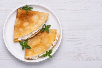 Thin pancakes, russian blini or french crepes with cottage cheese. Tasty homemade breakfast. Top...