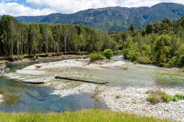 View of a beautiful landscape on a sunny day in southern Chile, featuring a turquoise river and green forests.