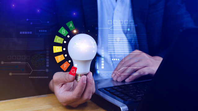 Energy efficiency concept, House energy efficiency or energy saving rate for reduce carbon footprint, hold light bulb with energy efficient rating class concept save cost green energy.