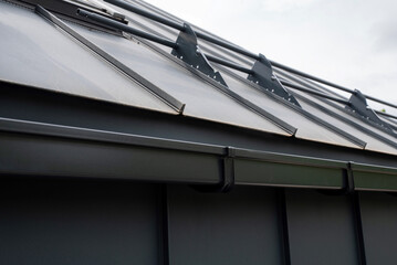 Gray rectangular metal rain gutter system with snow guard