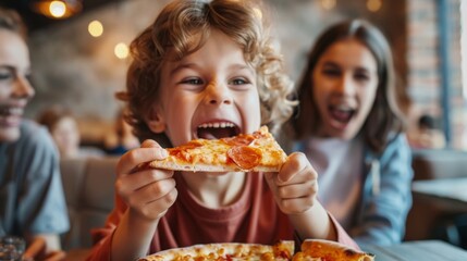 A young boy with curly hair happily eats a slice of pizza at a restaurant. He is smiling and enjoying his meal.
