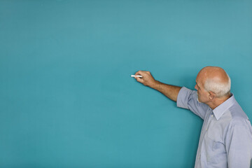 Focused man writing on blue blackboard, chalk