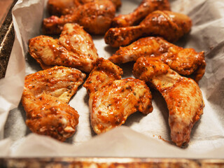 Asian style marinated chicken drumsticks and wings on cooking paper in a metal tray ready to be cooked. Fine poultry product for oven or barbecue. Simple popular traditionally meal.