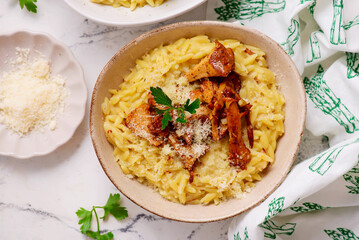 Orzotto with chanterelles, Parmesan cheese and parsley in a deep ceramic bowl.