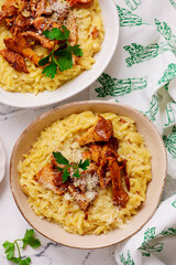 Orzotto with chanterelles, Parmesan cheese and parsley in a deep ceramic bowl.