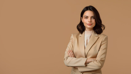 A young brunette woman in beige clothing stands against a solid beige background. Studio. Isolated beige background.