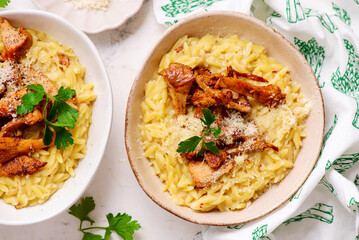Orzotto with chanterelles, Parmesan cheese and parsley in a deep ceramic bowl.