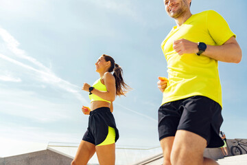 Fototapeta premium A joyful couple runs up stairs in a sunny urban setting, radiating health and happiness.