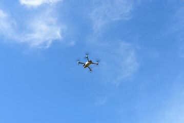 Drone performing capture in a sky with few clouds.