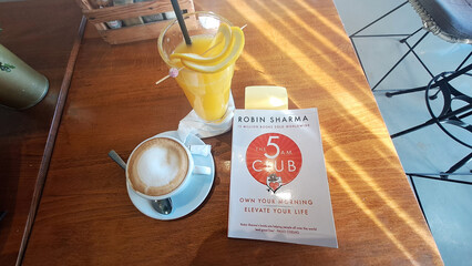 Enjoying morning coffee and orange juice with bestselling self-help book by robin sharma
