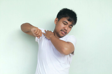 Tired upset young man wears white t-shirt suffering from pain, muscle spasm at workplace. Fatigue,...