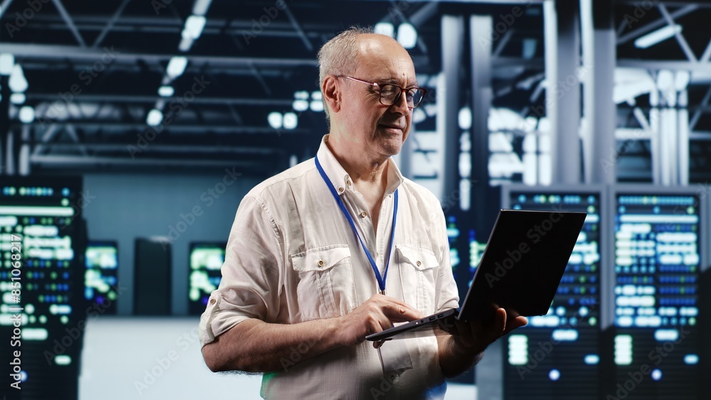 Poster focused it professional navigating network of blade servers in industrial hub. serviceman with lapto